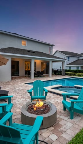 Dusk pool patio with fire pit, teal Adirondack chairs, and purple sky behind the villa